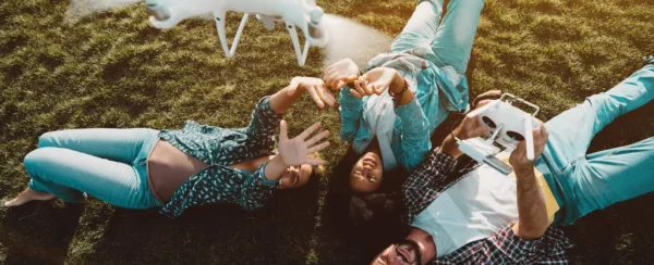 Jóvenes recostados en el césped mientras observan dron volando